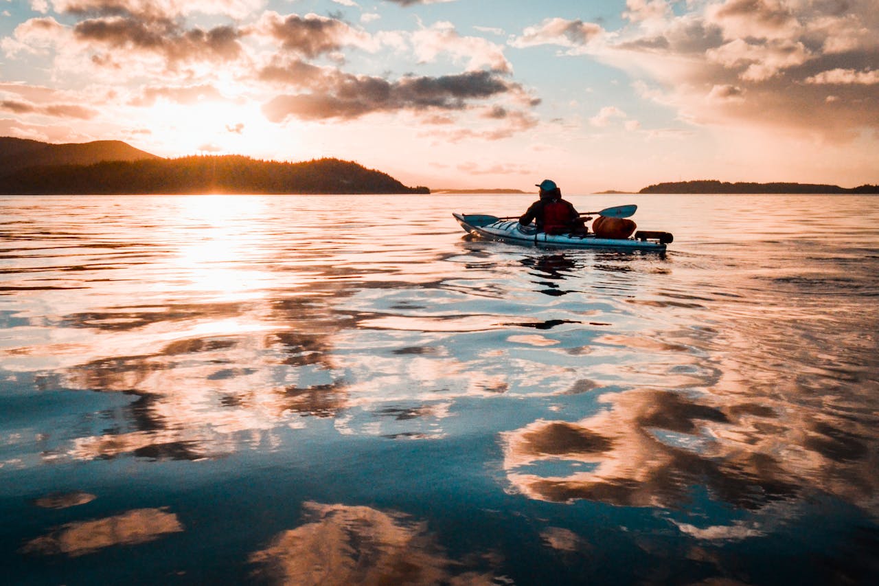 Person Sitting on Teal Kayak on Calm Water of River